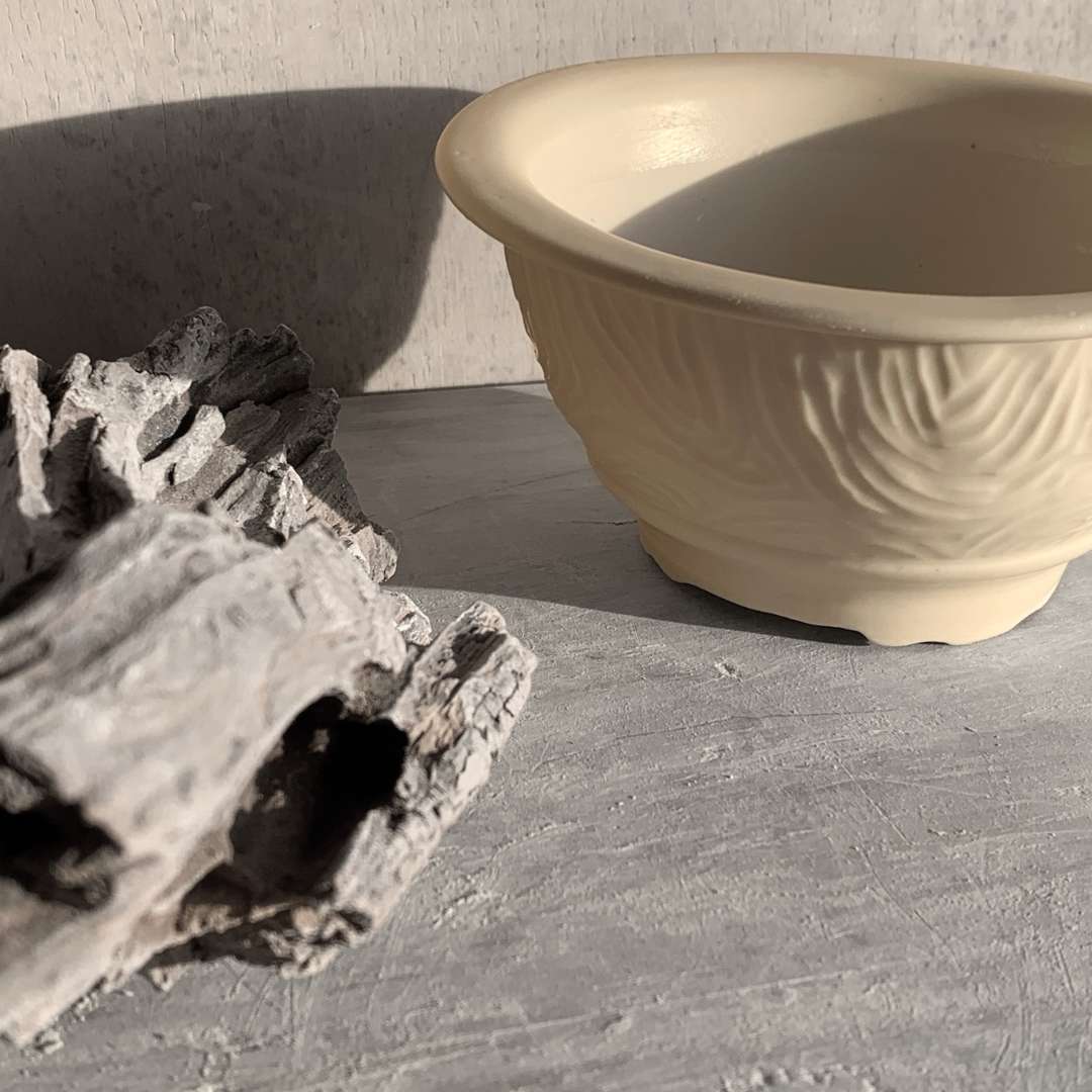 Detalle lateral de RESHI con relieve tallado sobre porcelana mate.